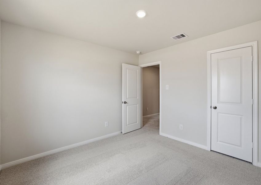 Carpeted secondary bedroom featuring an entry door and neutral finishes.
