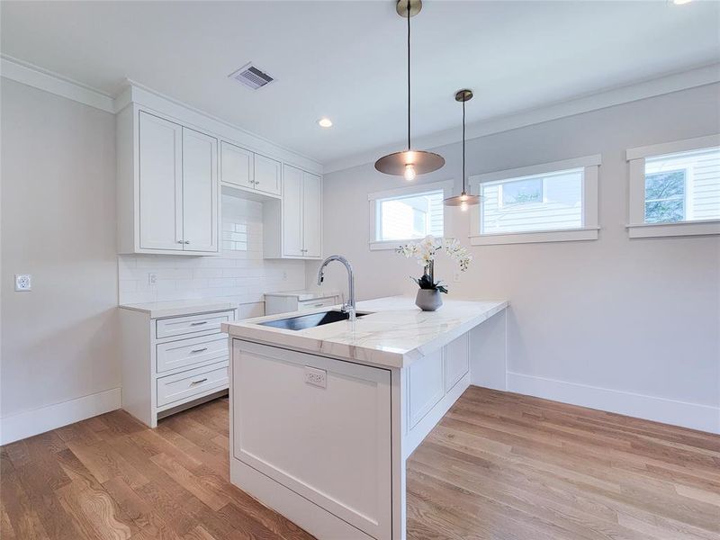 A better look at the garage apartment kitchen. Full island quartzite counter tops and modern lighting.