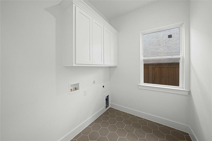 Washroom featuring electric dryer hookup, hookup for a gas dryer, cabinet space, dark tile patterned floors, and hookup for a washing machine Washroom featuring electric dryer hookup, hookup for a gas dryer, cabinet space, dark tile patterned floors, and hookup for a washing machine