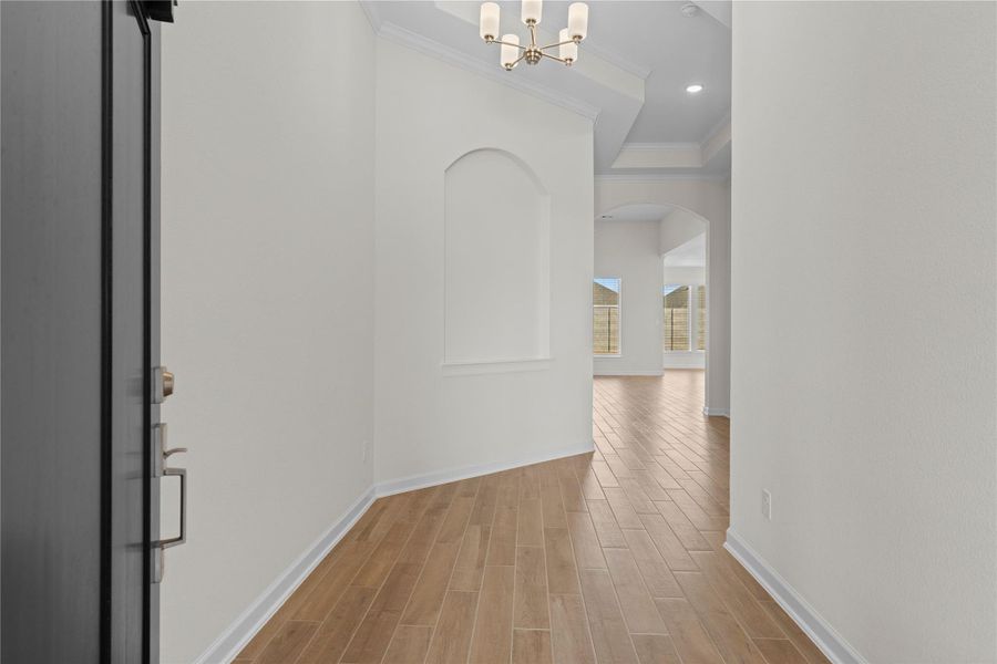 Inside, the grand formal entry opens to soaring ceilings and beautiful wood like tile flooring that flows seamlessly into the main living areas, creating an airy and elegant atmosphere, filled with natural light and a sense of openness that immediately makes you feel right at home.