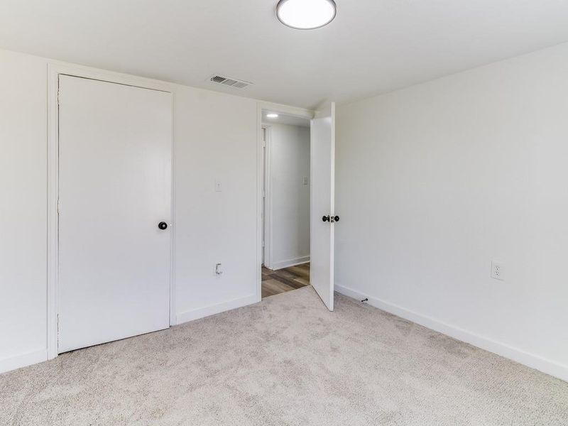 Unfurnished bedroom with carpet flooring and baseboards Unfurnished bedroom with carpet flooring and baseboards