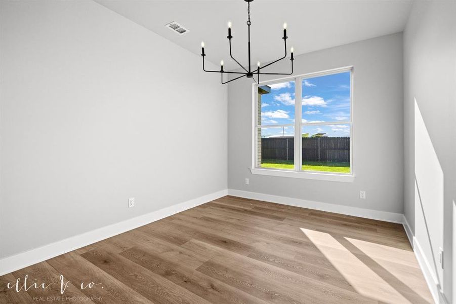 Unfurnished dining area featuring a chandelier and light wood-style floors