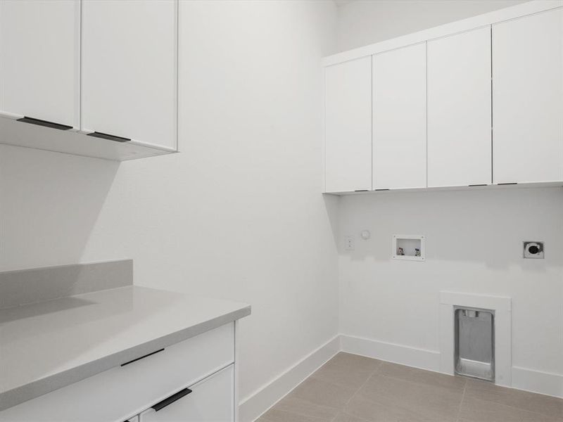 Washroom with cabinet space, washer hookup, hookup for an electric dryer, light tile patterned floors, and hookup for a gas dryer Washroom with cabinet space, washer hookup, hookup for an electric dryer, light tile patterned floors, and hookup for a gas dryer