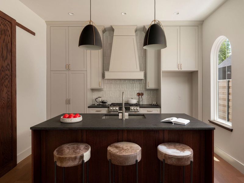 A well-appointed kitchen showcasing elegant cabinetry and a central island with sleek pendant lighting.