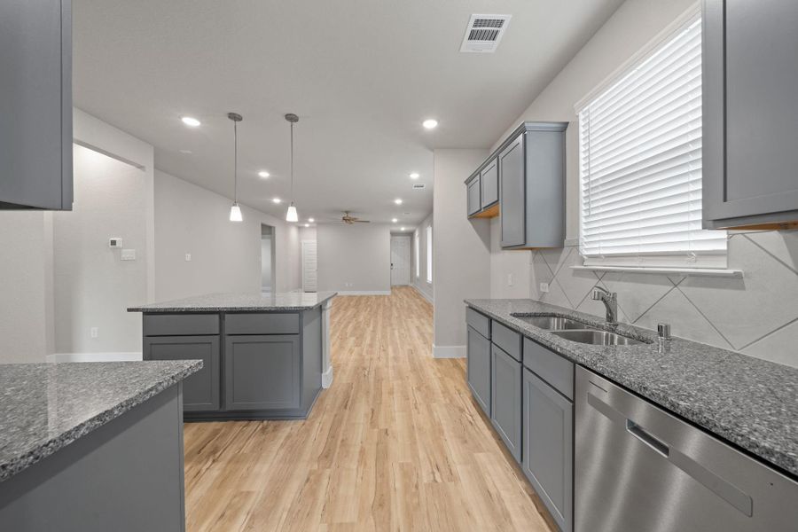 The light wood-look flooring adds warmth and contrast, while pendant lighting and recessed ceiling lights create a bright and inviting atmosphere.