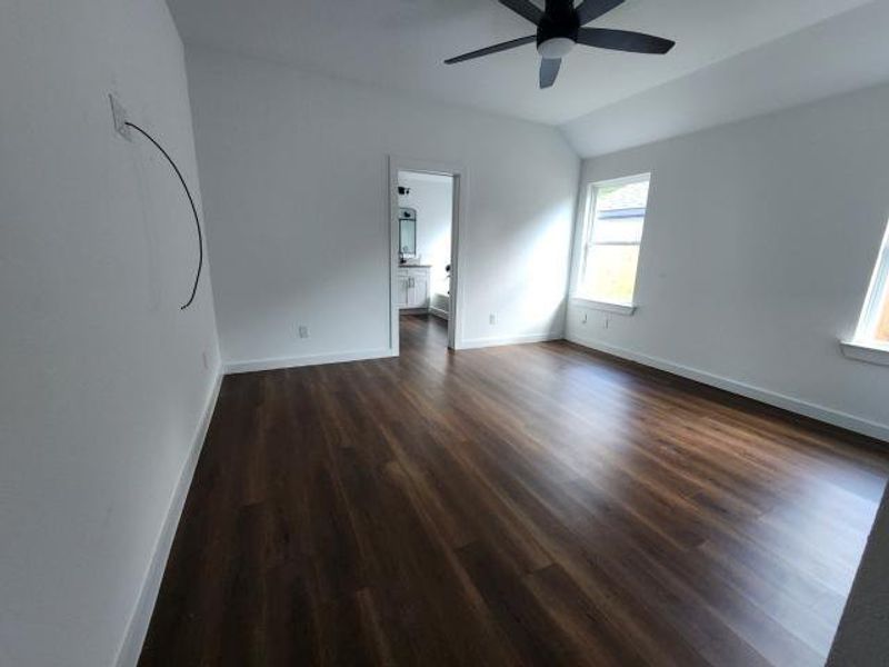Empty room featuring dark wood finished floors, lofted ceiling, and ceiling fan Empty room featuring dark wood finished floors, lofted ceiling, and ceiling fan