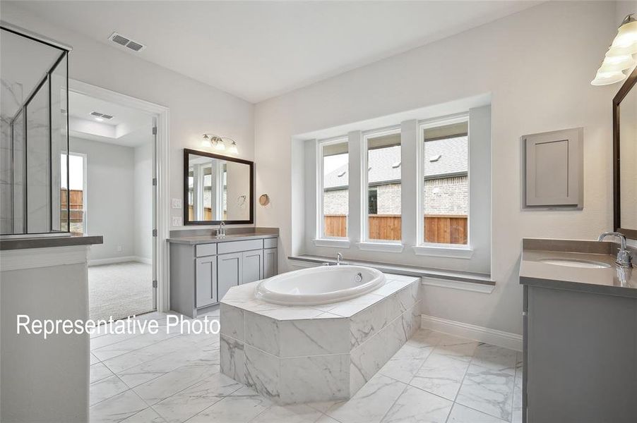 Bathroom with tiled bath, tile patterned floors, and double sink vanity