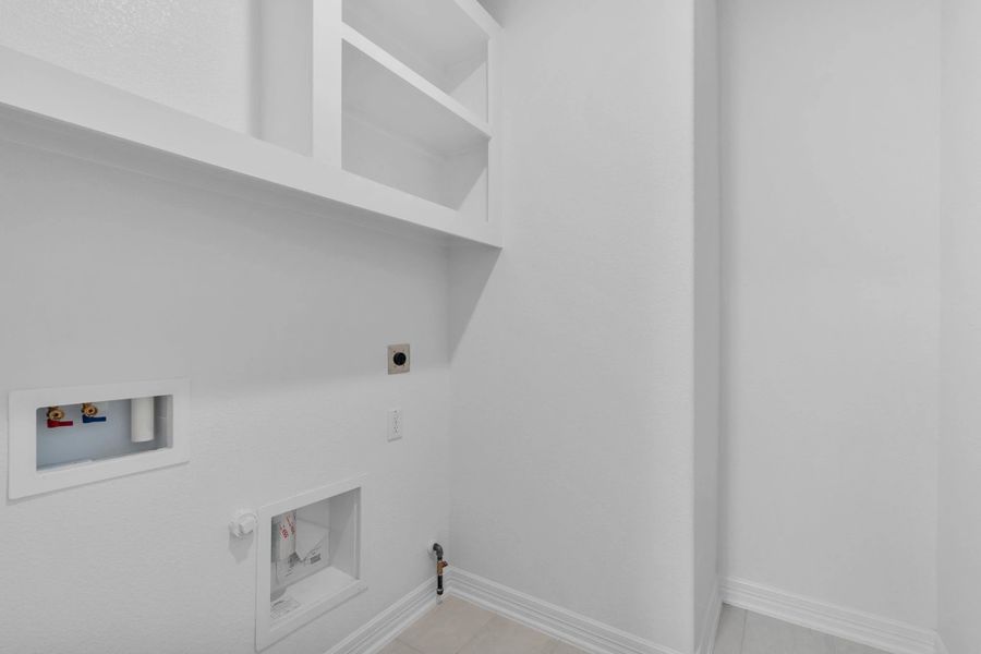 Functional utility room with custom shelSample product photo. Actual exterior and interior selections may vary by homesite. Photo may be virtually staged.ving and convenient laundry hookups.