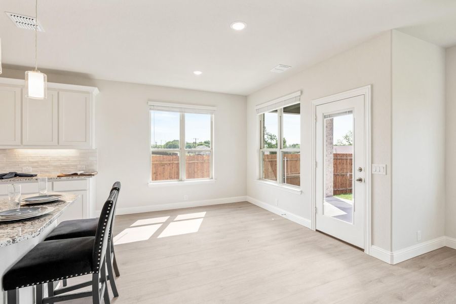 Bright dining area with light wood floors, white walls, and glass back door leading to backyard