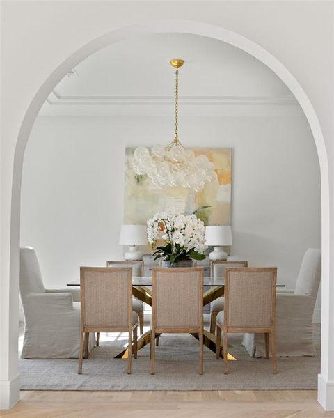 Dining area with wood-type flooring, ornamental molding, and a chandelier