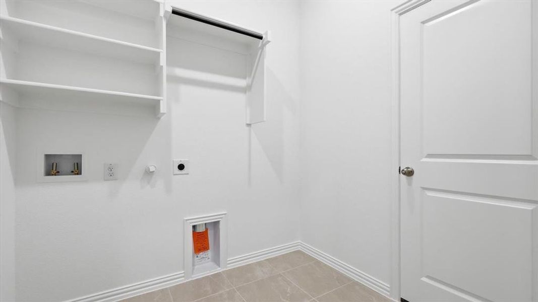Utility room featuring built-in shelving, a clothes rod, and tile flooring Utility room featuring built-in shelving, a clothes rod, and tile flooring