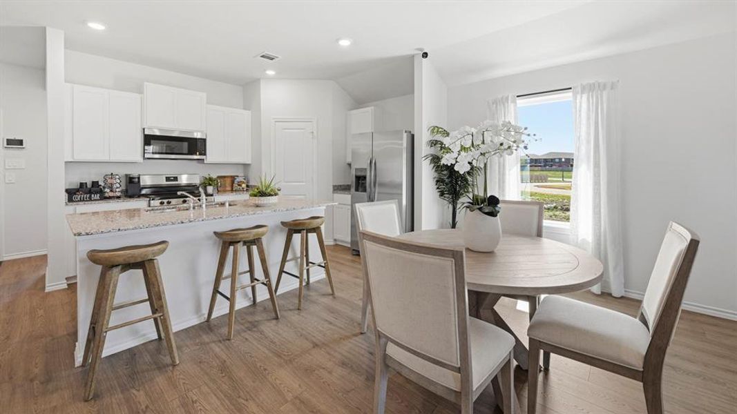 The kitchen features white cabinetry, stainless steel appliances, and a granite-topped island with seating
