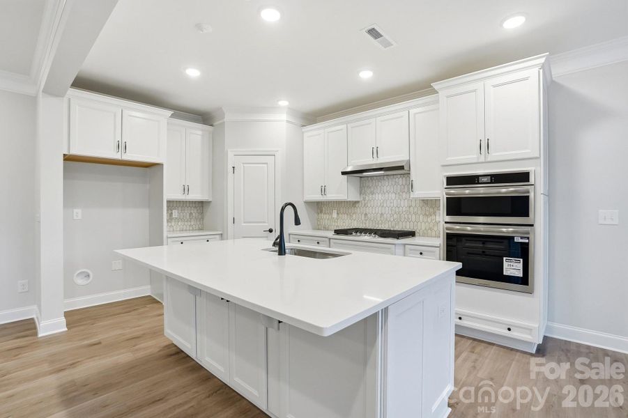 Kitchen features white cabinets, black hardware and quartz countertops