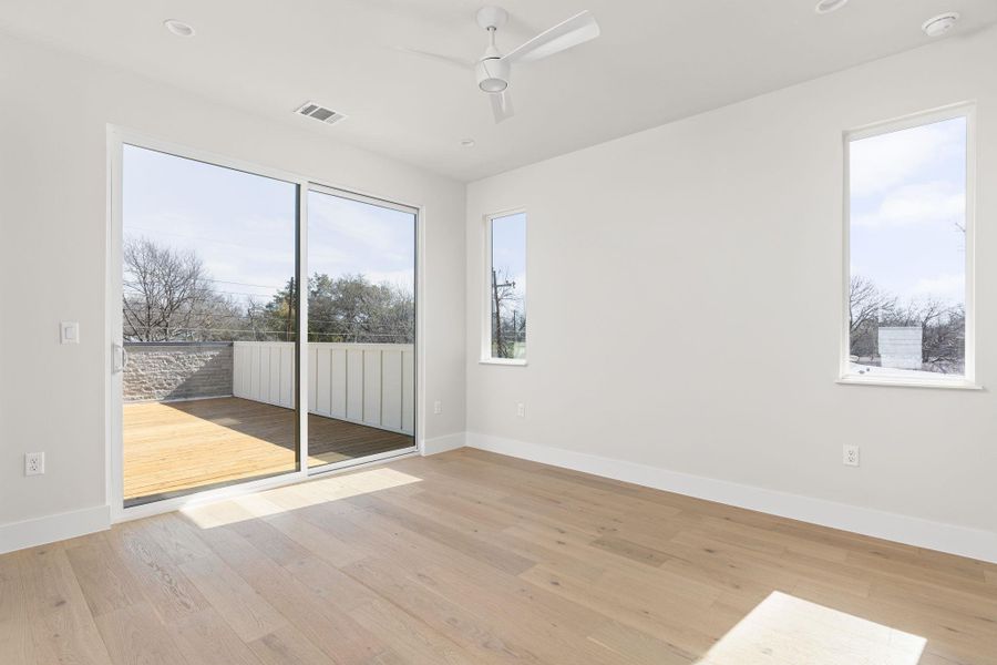 Empty room with light wood-type flooring, visible vents, baseboards, and a ceiling fan