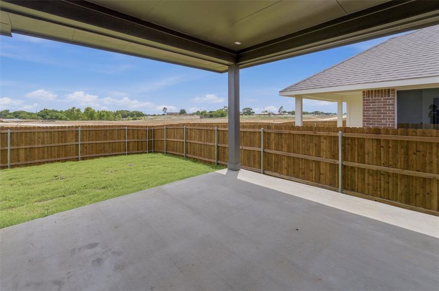 Covered patio with a concrete surface, enclosed by a wood privacy fence Covered patio with a concrete surface, enclosed by a wood privacy fence