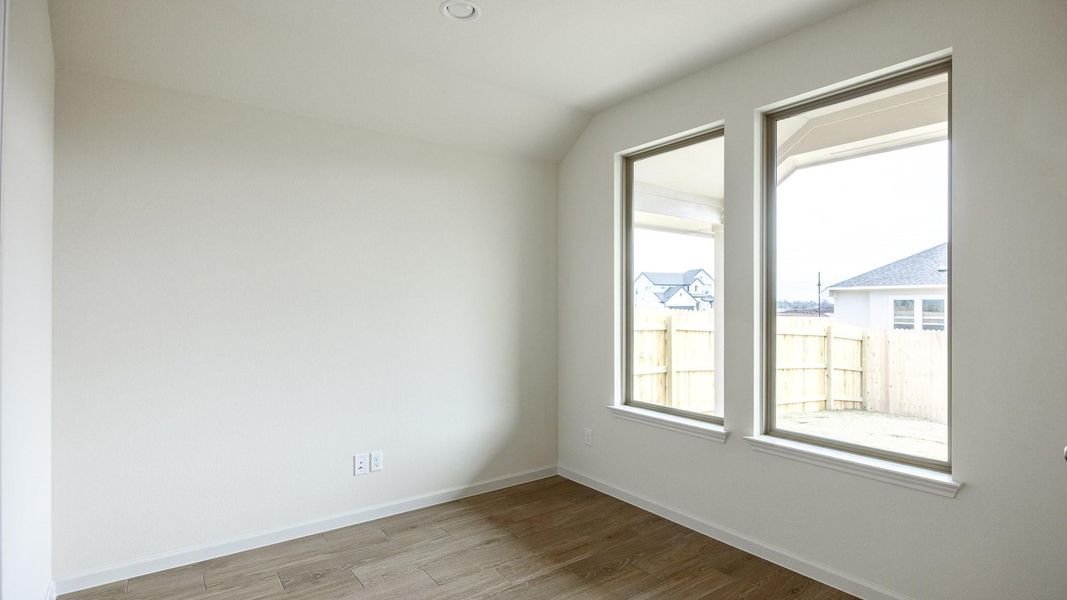 Empty room featuring lofted ceiling and light hardwood / wood-style floors