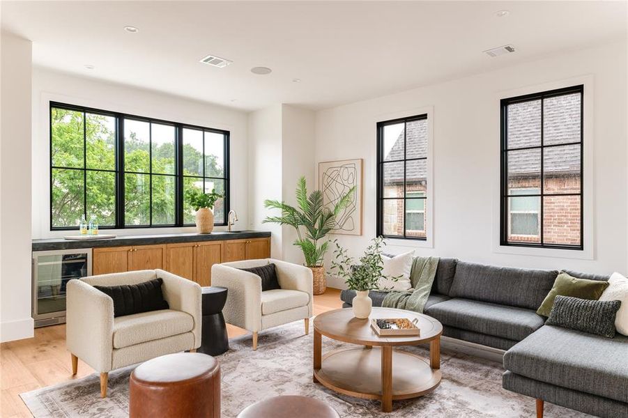 Living area featuring beverage cooler, light wood-type flooring, and wet bar