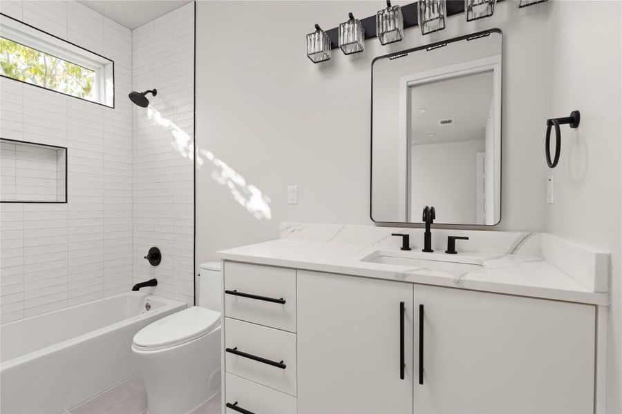 Clean lines and stone counters define this modern bathroom with its tiled shower and tub.