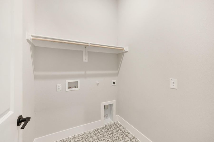 Laundry room with wall shelf, washer and dryer hookups, and patterned tile floor Laundry room with wall shelf, washer and dryer hookups, and patterned tile floor