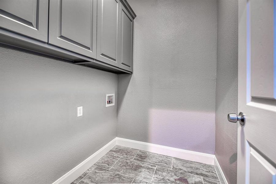 Clothes washing area featuring cabinets, light tile floors, and hookup for a washing machine