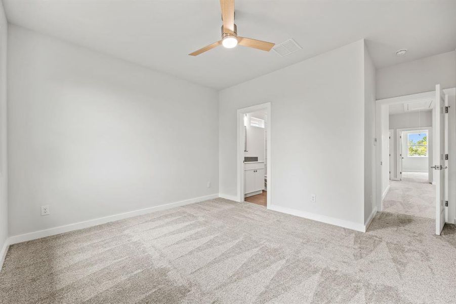 Unfurnished bedroom with light carpet, ensuite bathroom, and ceiling fan