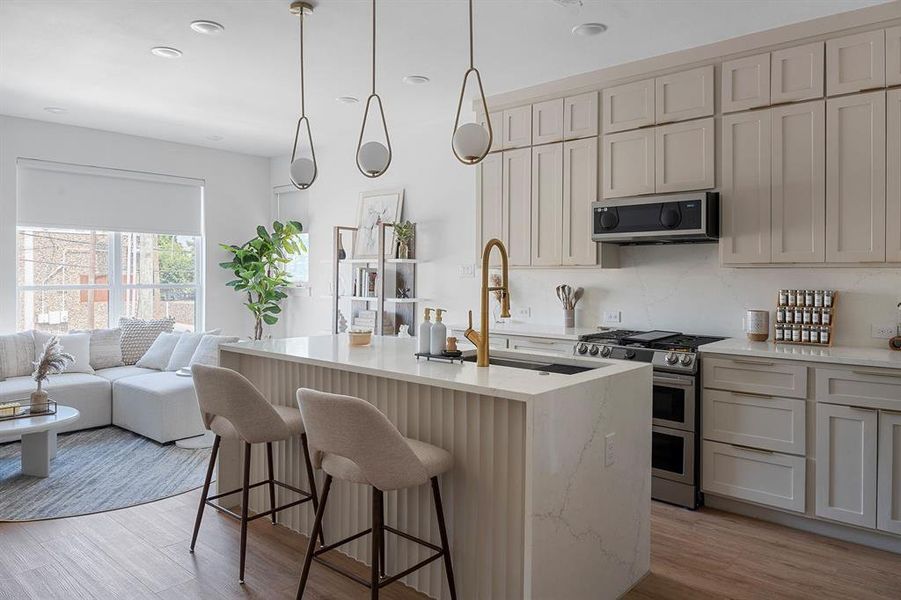 Kitchen featuring stainless steel appliances, light stone counters, cream cabinetry, light wood-style floors, and recessed lighting Kitchen featuring stainless steel appliances, light stone counters, cream cabinetry, light wood-style floors, and recessed lighting