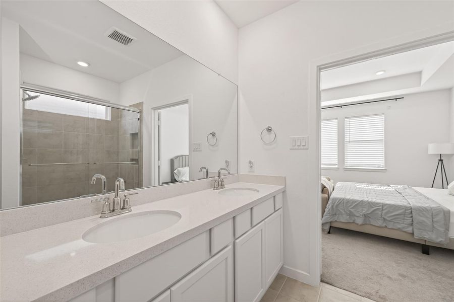 The primary bath features double vanities with expansive wall-to-wall mirrors and generous drawer and cabinet storage, creating a well-organized and highly functional space. Thoughtfully designed for both convenience and comfort, it offers an ideal setting for daily routines while maintaining a polished and refined look.