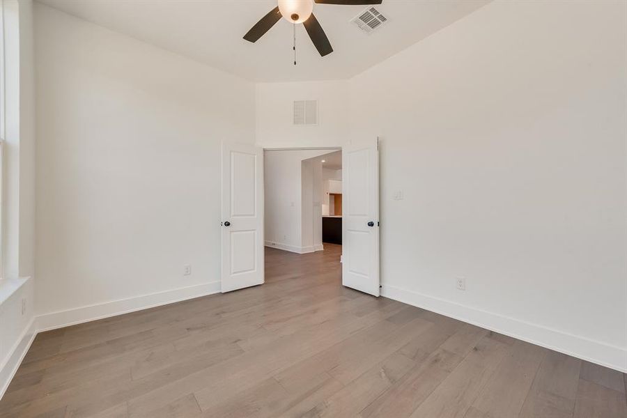 Spare room featuring wood finished floors, ceiling fan, and a high ceiling Spare room featuring wood finished floors, ceiling fan, and a high ceiling