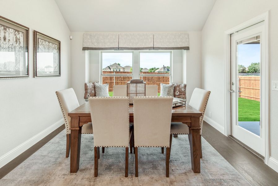 Dining room with wooden table, six upholstered chairs, large window, and glass door to backyard