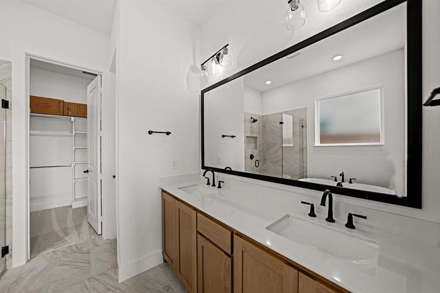 Bathroom featuring a stall shower, a spacious closet, double vanity, light marble finish flooring, and a freestanding tub
