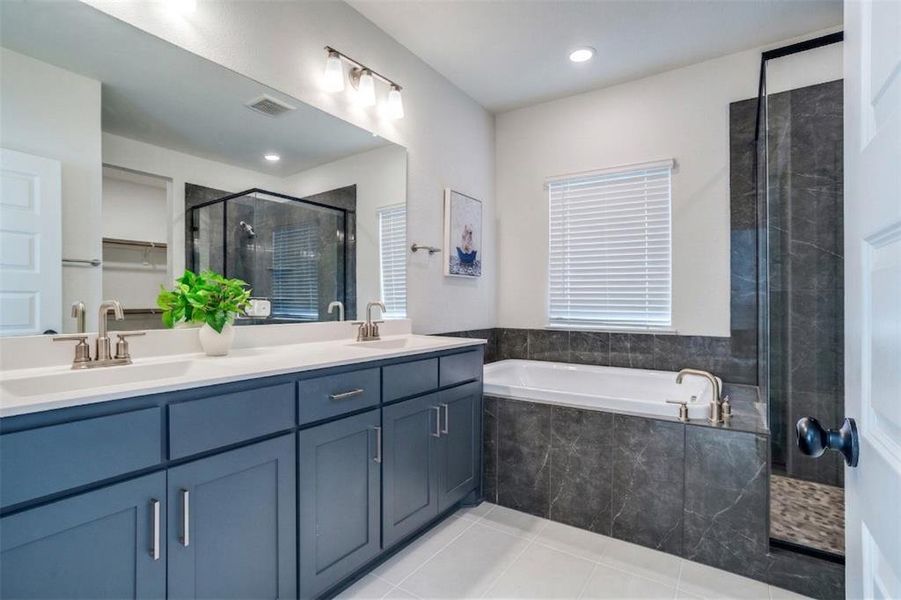 Bathroom with double vanity, a shower stall, light tile patterned floors, a bath, and a spacious closet