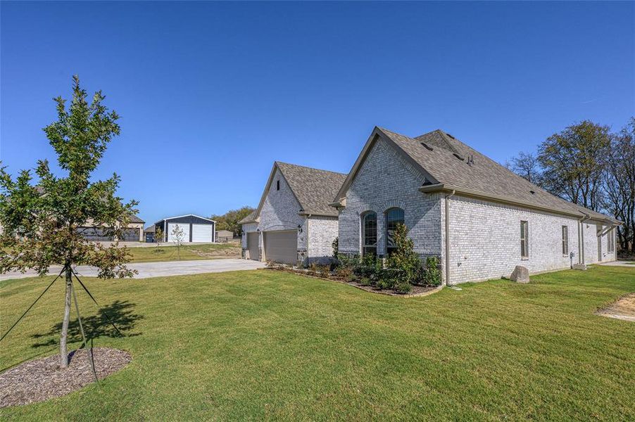 View of side of home with a garage, a lawn, brick siding, and driveway View of side of home with a garage, a lawn, brick siding, and driveway