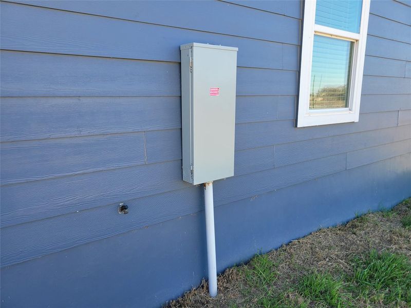 A glimpse of the home's exterior showcases its clean siding and a practical electrical panel.