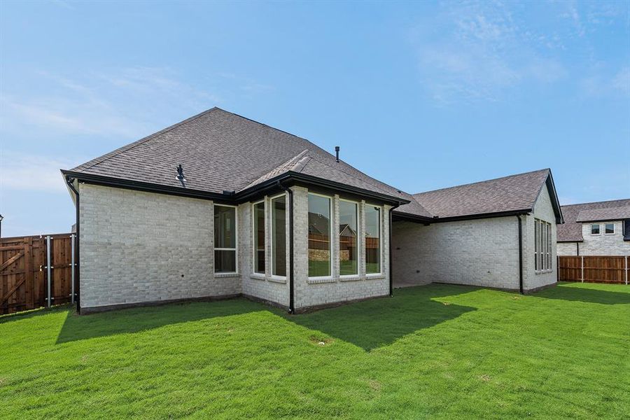 Rear view of property with a fenced backyard, brick siding, a shingled roof, and a patio