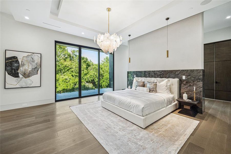 In this primary bedroom, adorned with designer neutral wall paint that sets a serene backdrop for relaxation, the ambiance is further elevated by the warmth of stained White Oak Engineered Hardwood Flooring, complemented by the gentle glow of recessed LED lighting, creating a tranquil haven where comfort and style harmonize effortlessly.