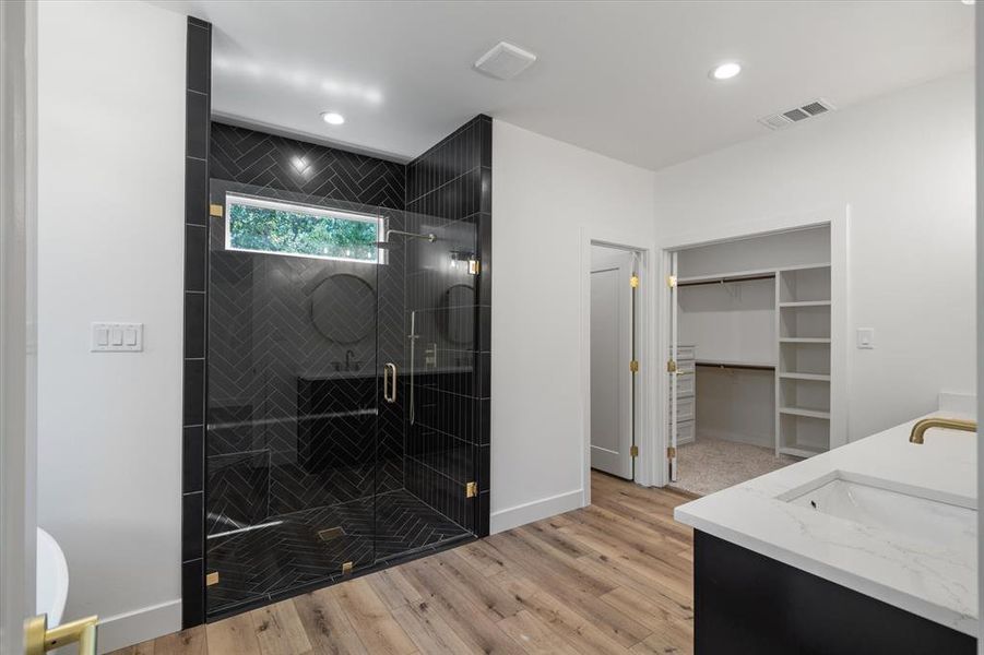 Full bathroom with a spacious closet, double vanity, light wood-style floors, a shower stall, and recessed lighting