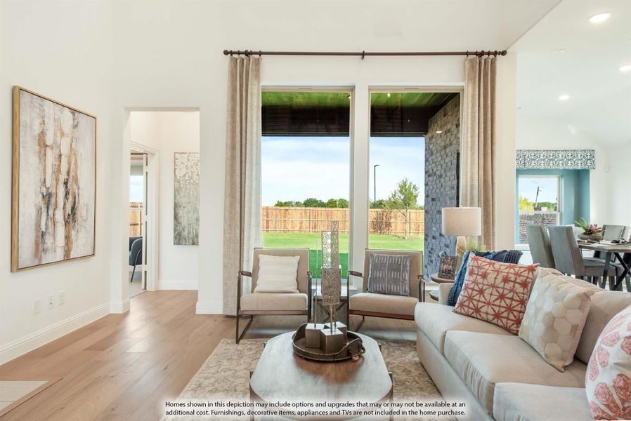 Living room with hardwood floors, large windows, neutral sofa, accent chairs, and backyard view
