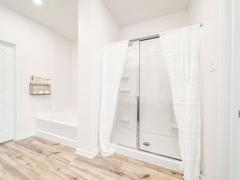 Bathroom featuring a shower stall, a bath, and wood finished floors