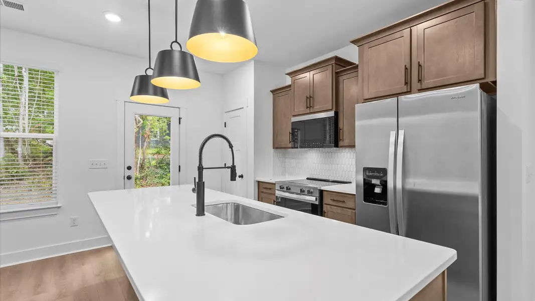 Vibrant and open kitchen centered around a 9-foot island with elegant pendant lighting above Vibrant and open kitchen centered around a 9-foot island with elegant pendant lighting above