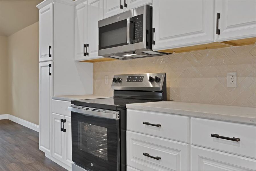 Kitchen featuring white cabinets, baseboards, appliances with stainless steel finishes, and light countertops Kitchen featuring white cabinets, baseboards, appliances with stainless steel finishes, and light countertops