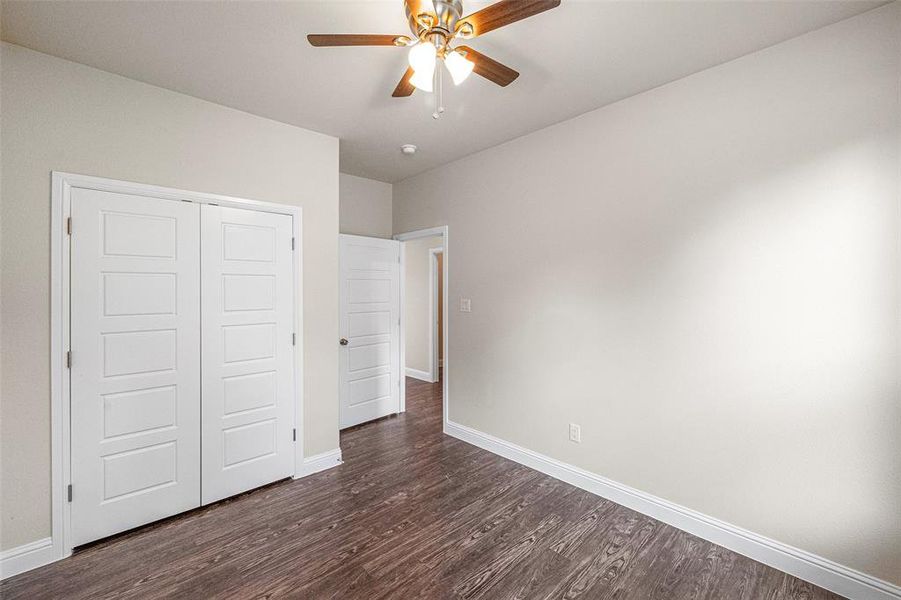 Unfurnished bedroom featuring a closet, ceiling fan, and dark hardwood / wood-style flooring