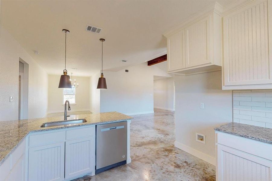 Kitchen with light stone countertops, sink, stainless steel dishwasher, and decorative backsplash