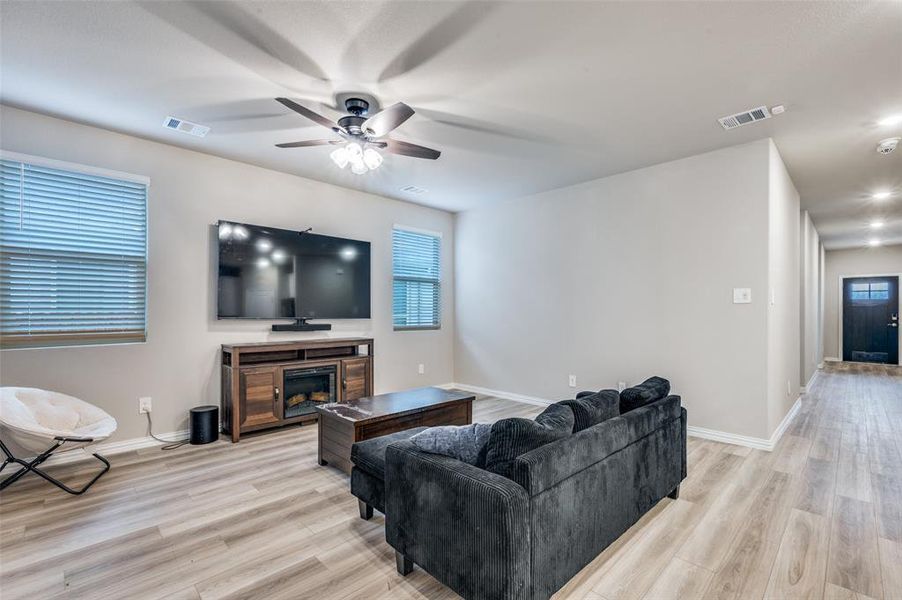 Living room with a ceiling fan, light wood-style floors, and a fireplace