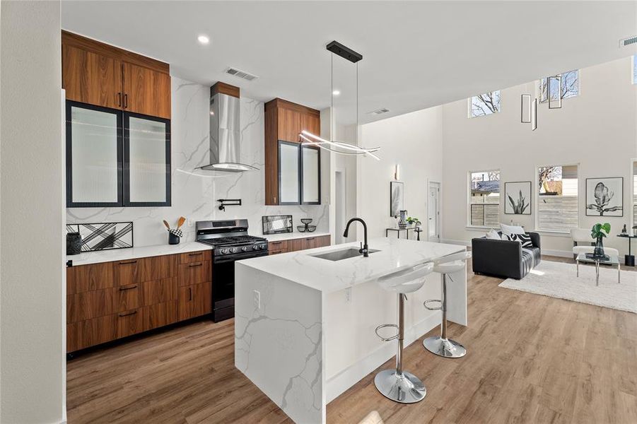 Kitchen featuring black appliances, light stone countertops, open floor plan, a kitchen island with sink, and tasteful backsplash