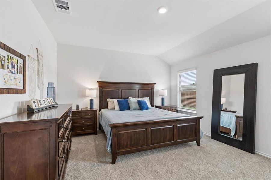 Bedroom featuring light carpet and vaulted ceiling Bedroom featuring light carpet and vaulted ceiling
