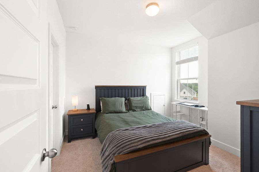 A well-lit bedroom provides ample natural light through a large window, featuring a cozy ambiance.