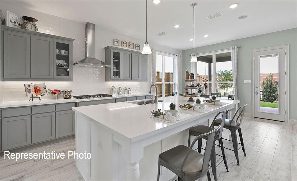 Kitchen featuring light gray cabinetry, a white subway tile backsplash, and light wood-finish plank flooring