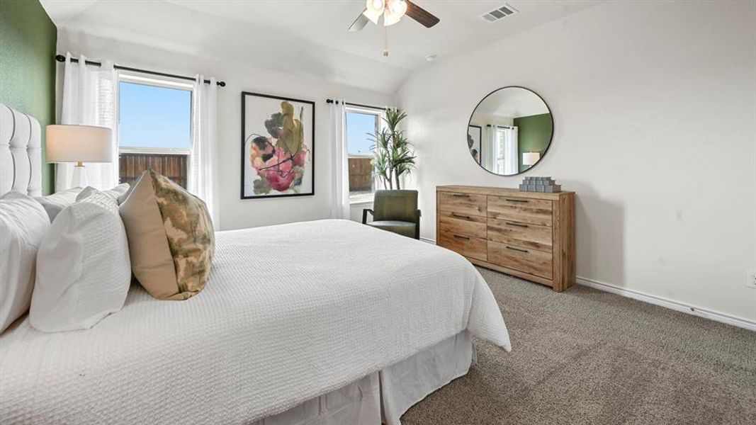 Carpeted bedroom featuring vaulted ceiling and a ceiling fan