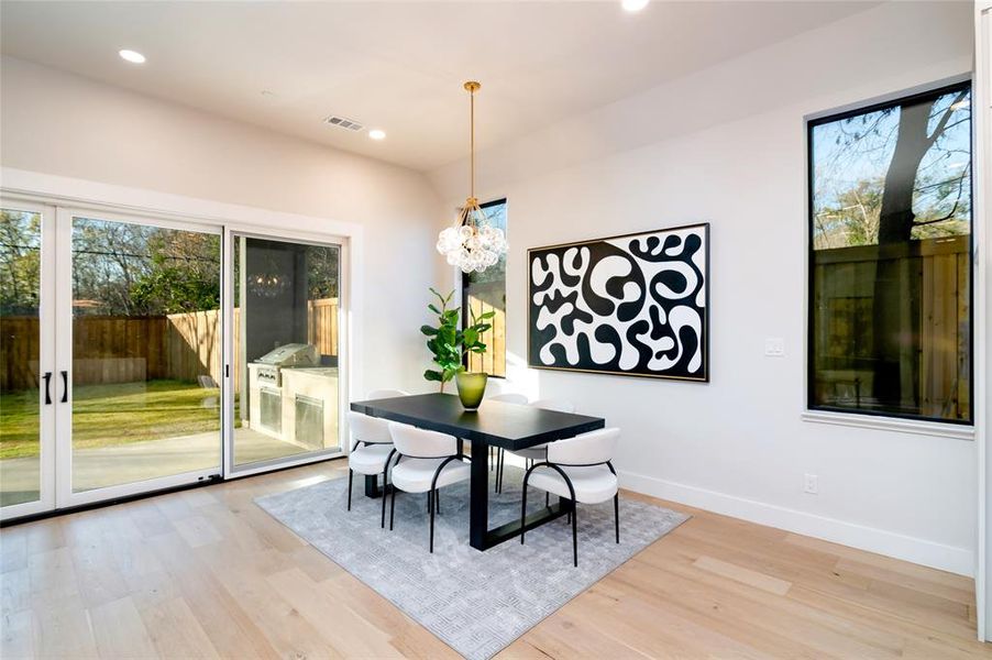 Dining space with light hardwood / wood-style flooring and a chandelier