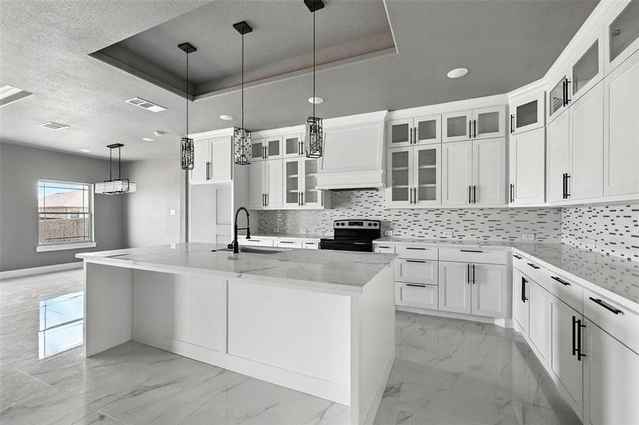 Kitchen featuring a tray ceiling, tasteful backsplash, light marble finish floors, recessed lighting, and a textured ceiling Kitchen featuring a tray ceiling, tasteful backsplash, light marble finish floors, recessed lighting, and a textured ceiling